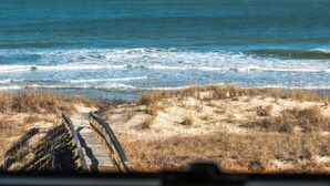 A beach with a wooden boardwalk leading to the water. - Over The Moon by Carolina Retreats (Kure Beach)