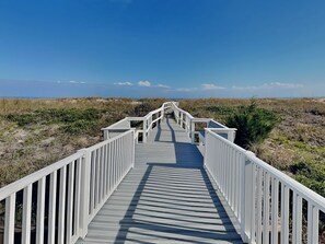 A wooden boardwalk leading to a beach with white railings. - Seaship by Carolina Retreats (Carolina Beach)
