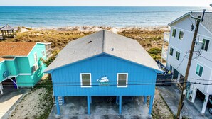 A blue house with a sailboat logo, located near a beach with a clear view of the ocean. - Seaship by Carolina Retreats (Carolina Beach)
