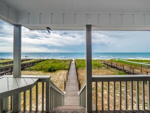 A wooden boardwalk leading to a beach with a view of the ocean. - Summer Place by Carolina Retreats (Kure Beach)