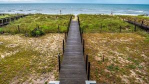 A wooden boardwalk leading to a beach with a clear view of the ocean. - Summer Place by Carolina Retreats (Kure Beach)