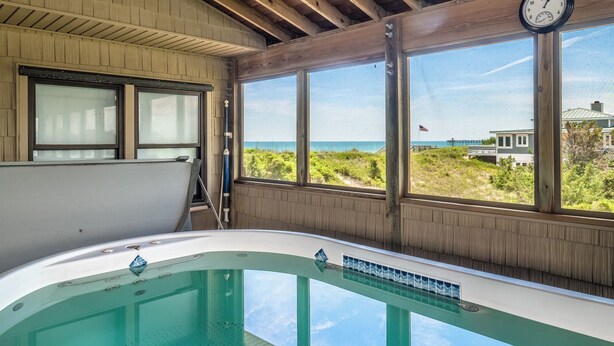Ein Zimmer mit großem Fenster, Holzbalkendecke und einer Badewanne.