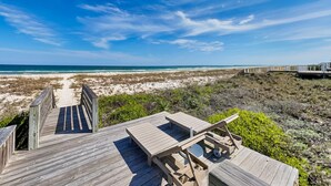 Eine Holzterrasse mit Blick auf Strand und Meer.