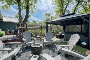 Ein Sitzbereich im Freien mit Adirondack-Stühlen, einer Feuerstelle und einer überdachten Terrasse.