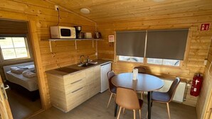 Una cabaña de madera acogedora con kitchenette, comedor y zona de descanso.