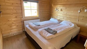 Un dormitorio con paneles de madera, una cama, un ventanal y una mesita de noche.