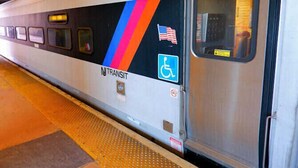 Un tren con un lateral que muestra el logotipo de NTRANSIT, una bandera estadounidense y un símbolo de accesibilidad para sillas de ruedas.