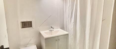 A small bathroom with a toilet, a sink, and a shower curtain.