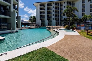 Un hôtel doté d’une grande piscine extérieure, de nombreux balcons et de palmiers.