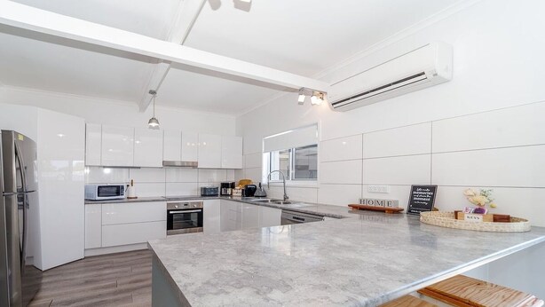 A modern kitchen with white cabinetry, a granite countertop, and a built-in oven.