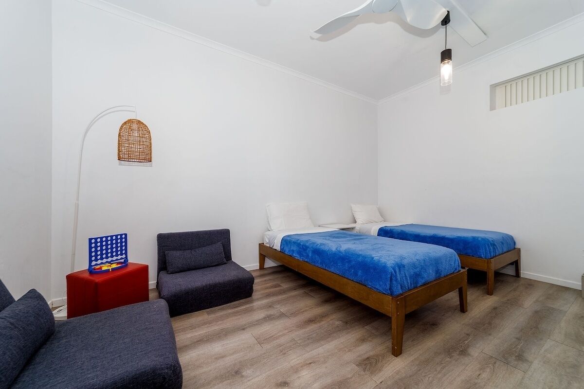 Ein Schlafzimmer mit zwei Einzelbetten, einem Deckenventilator, einem roten Nachttisch und einer Stehlampe.