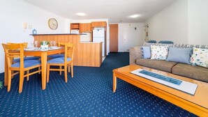 Un espacio habitable compacto con comedor, kitchenette y un sofá con cojines estampados.