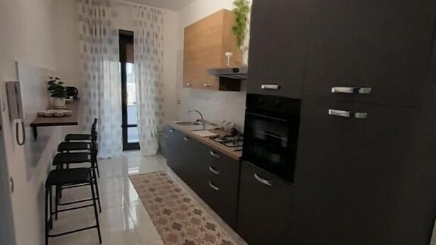 Een moderne keuken met donkere kastjes, een centraal eiland en een kamerbreed tapijt met een patroon.