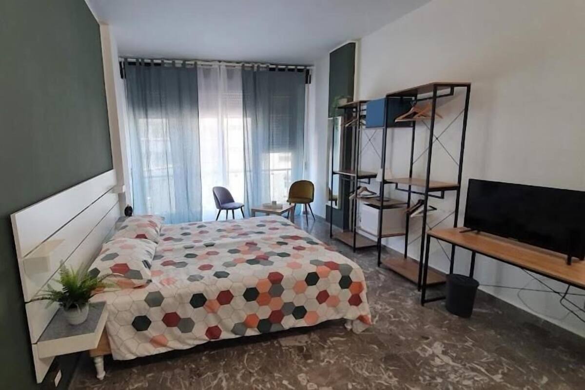 A bedroom with a bed, a desk, a chair, a TV, and a wardrobe.