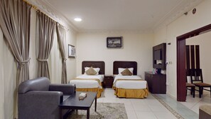 Ein Hotelzimmer mit zwei Betten, einem Sofa, einem Tisch, einem Fernseher und einem Bild an der Wand.