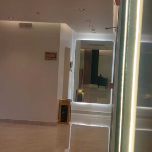A hallway with a door leading to a room, a wall-mounted sign, and a small table with a telephone. - Wahat Al Madinah Hotel Apartments (Madinah)