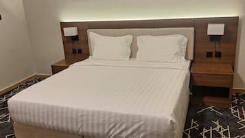 A hotel room with a large bed, two bedside tables, and a patterned carpet.