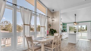 A spacious kitchen with a dining area, large windows, and a view of the outdoors. - Bates Avenue House (Indian Rocks Beach)