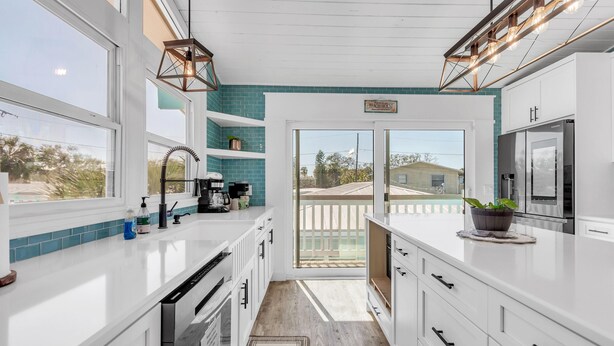 A modern kitchen with white cabinets, a large window, and a sign reading "Peach House". - Bates Avenue House (Indian Rocks Beach)