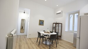 A compact kitchen with a refrigerator, a dining table with chairs, and a window. - Devalù Politeama elegante appartamento al centro (palermo)