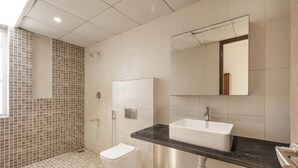 A modern bathroom with a toilet, sink, and shower. - Golf View Home by Stayjade (Hosur)
