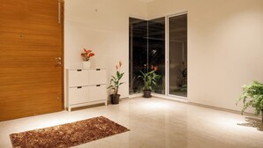 A modern interior with a wooden door, a white cabinet, and two potted plants. - Golf View Home by Stayjade (Hosur)
