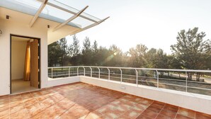 A spacious balcony with a glass ceiling, offering a view of trees and a park. - Golf View Home by Stayjade (Hosur)