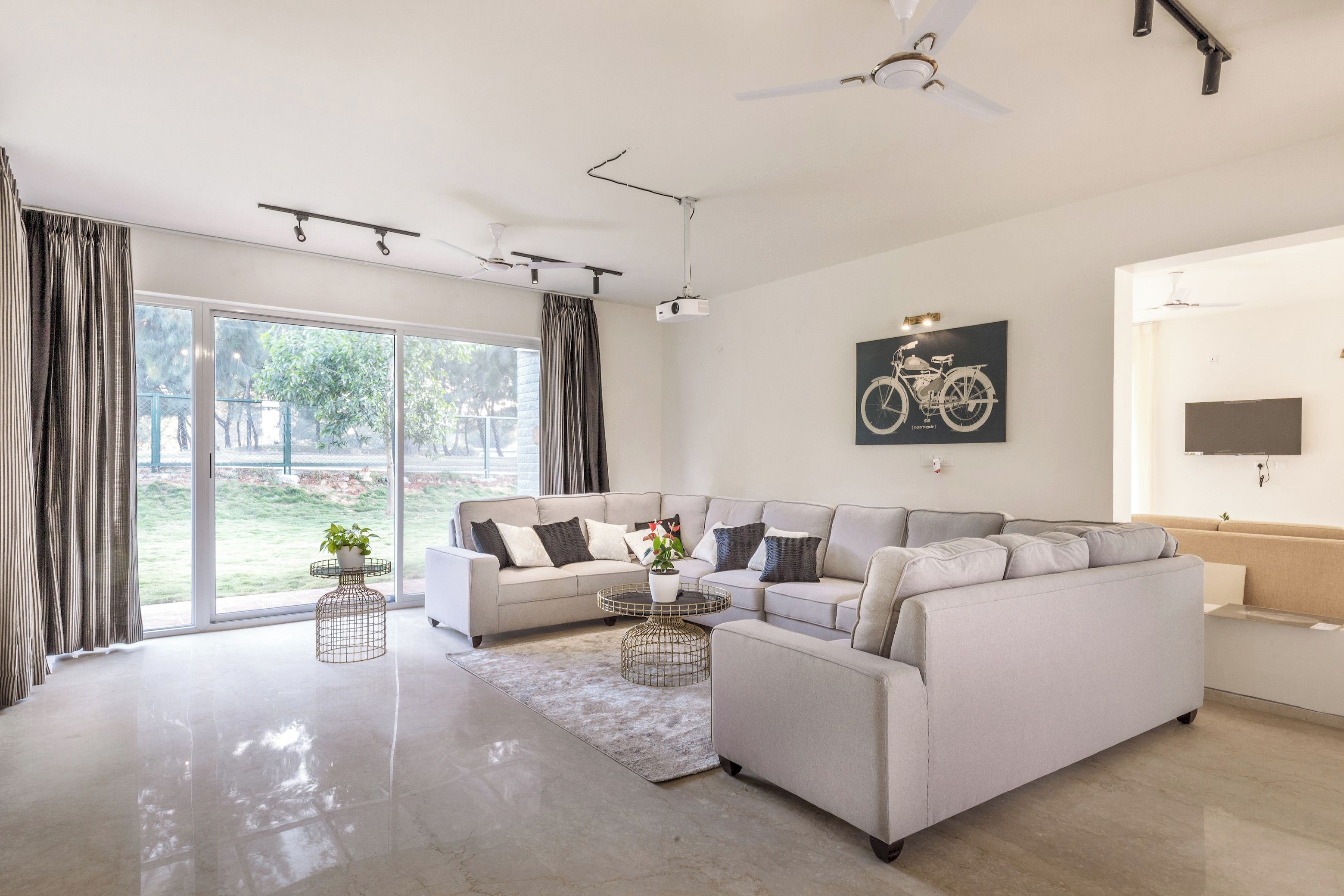 Una sala de estar moderna con un sofá modular, una mesa de centro y un ventanal con cortinas.