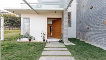 A modern house with a glass extension, a stone wall, and a well-maintained lawn.