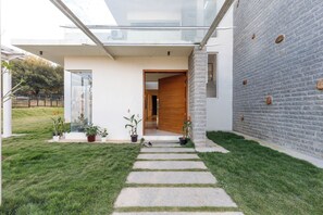 Una casa moderna con un cerramiento de vidrio, una pared de piedra y un césped cuidado.