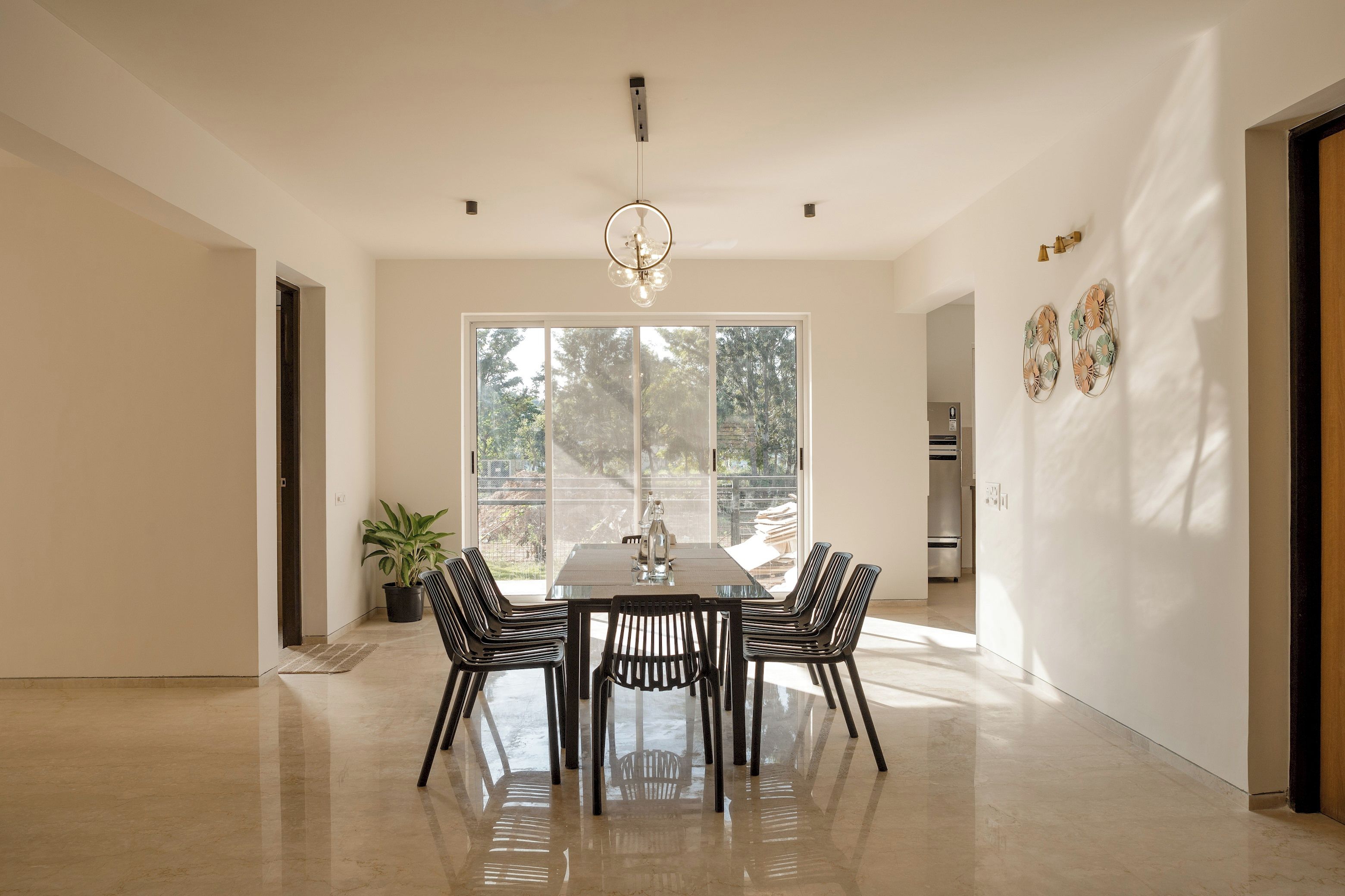 A modern dining room with a rectangular table and six chairs, large windows, and a potted plant.
