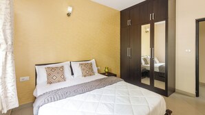 A bedroom with a large bed, a wardrobe, and a nightstand. - Aspire Heights by Red Olive (Bengaluru)