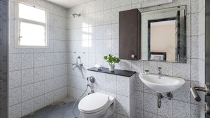 A modern bathroom with a toilet, sink, and shower. - Aspire Heights by Red Olive (Bengaluru)