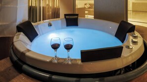 A hot tub with two glasses of wine, wooden seating, and a ceiling light.