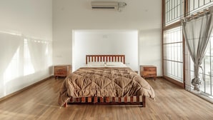 Un dormitorio con cama de madera, un ventanal con vistas y aire acondicionado instalado en la pared.