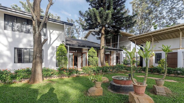 Una casa moderna con un jardín bien cuidado, que incluye un estanque y diversas plantas.