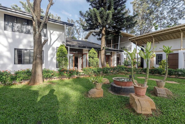 A modern house with a well-maintained garden, including a pond and various plants.