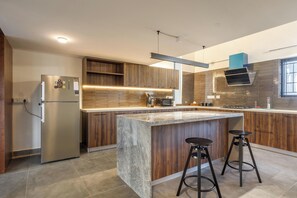 A modern kitchen with a central island, wooden cabinets, stainless steel appliances, and a built-in oven.
