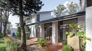 Una casa moderna con un porche cubierto, un jardín con diversas plantas y un cielo despejado.