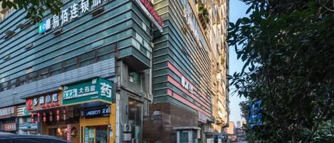 Un edificio de varios pisos con diferentes comercios en la planta baja, incluyendo una farmacia y un restaurante.
