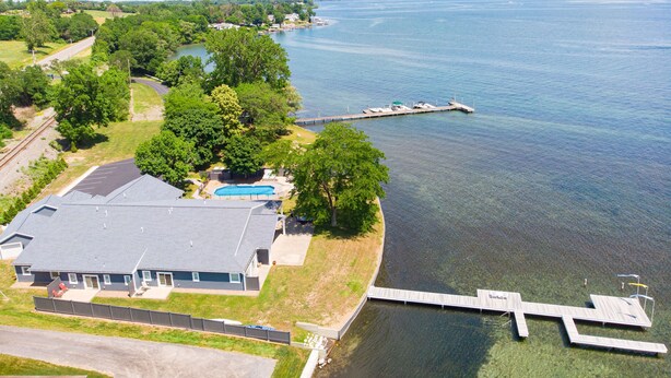 Vista aérea de una propiedad junto al lago, con muelle, piscina y una casa con amplio garaje.