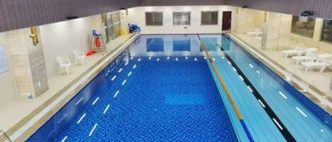 An indoor swimming pool with clear lanes, a changing room area, and a seating area with chairs.