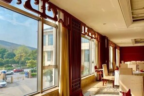 A hotel room with large windows, a view of the outside, and a dining area with tables and chairs. - Yushan Hotel (Changshu)
