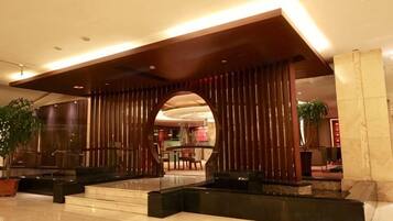 A lobby with a modern design, featuring a reception desk, seating areas, and a large archway.