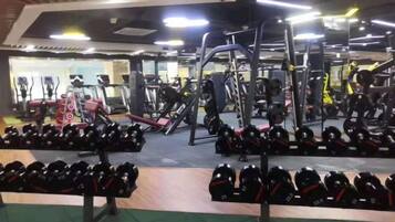 Un gimnasio con diversos equipos de ejercicio, bancos de pesas y mancuernas.