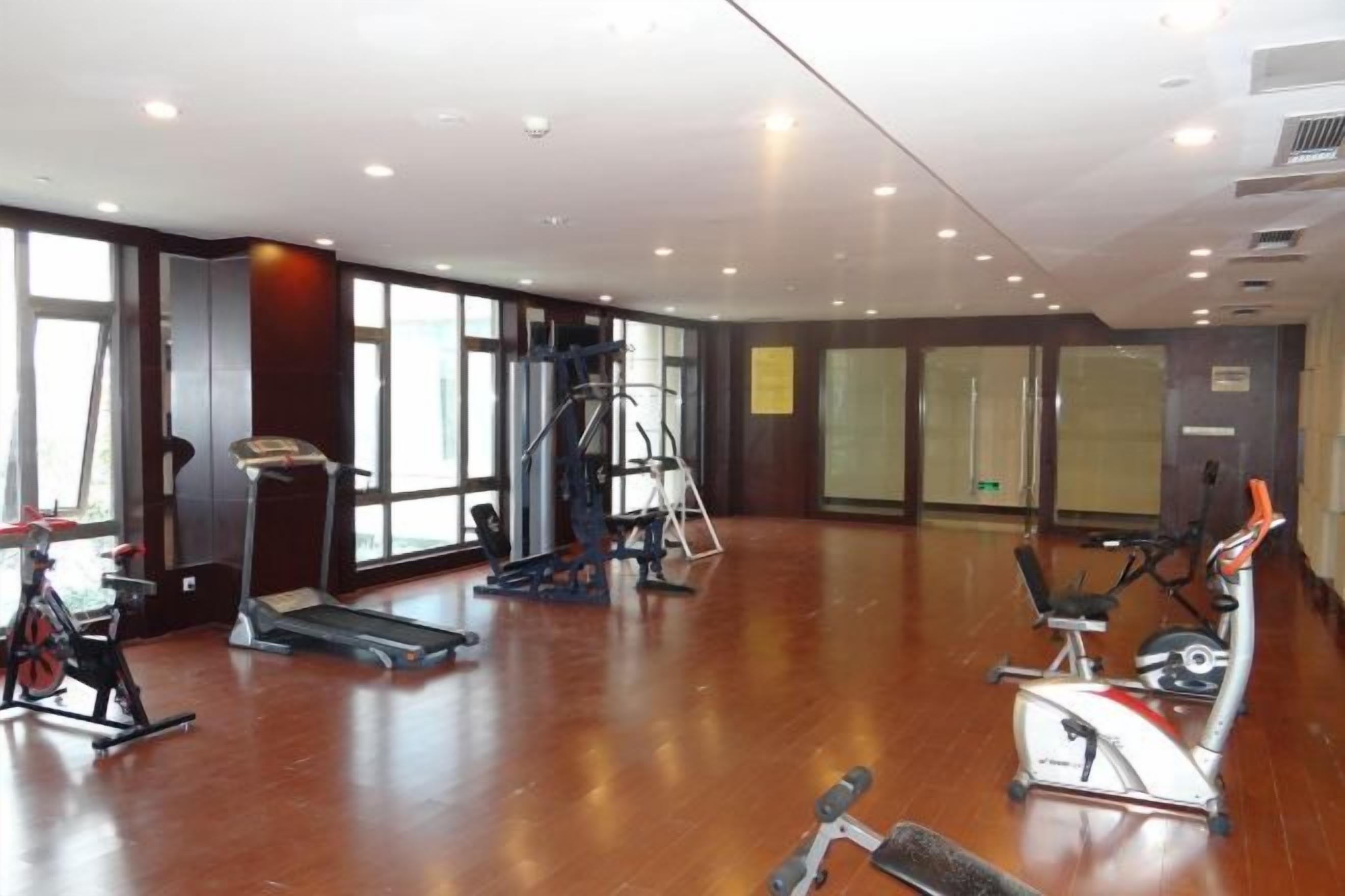 A spacious gym with cardio machines, free weights, and a mirrored wall.