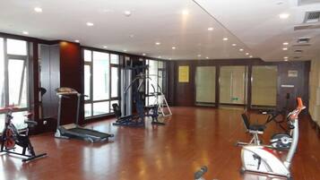 A spacious gym with cardio machines, free weights, and a mirrored wall.