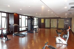 A spacious gym with cardio machines, free weights, and a mirrored wall. - Yushan Hotel (Changshu)