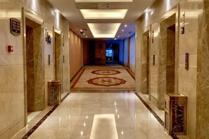 A hotel corridor with marble flooring, a patterned carpet, and doors with numbered signs. - Yushan Hotel (Changshu)