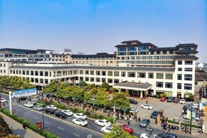 A multi-story building with a parking lot and a pedestrian area in front. - Yushan Hotel (Changshu)